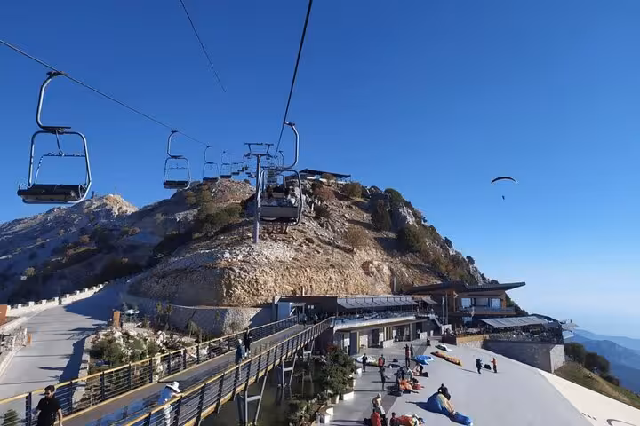 Chairlift ascending the rocky landscape in Fethiye, with paragliding launch area and stunning mountain vistas below.