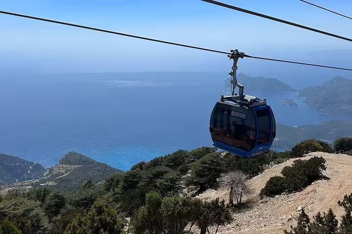 Scenic cable car ride over lush forests and turquoise waters in Fethiye, offering breathtaking panoramic views.
