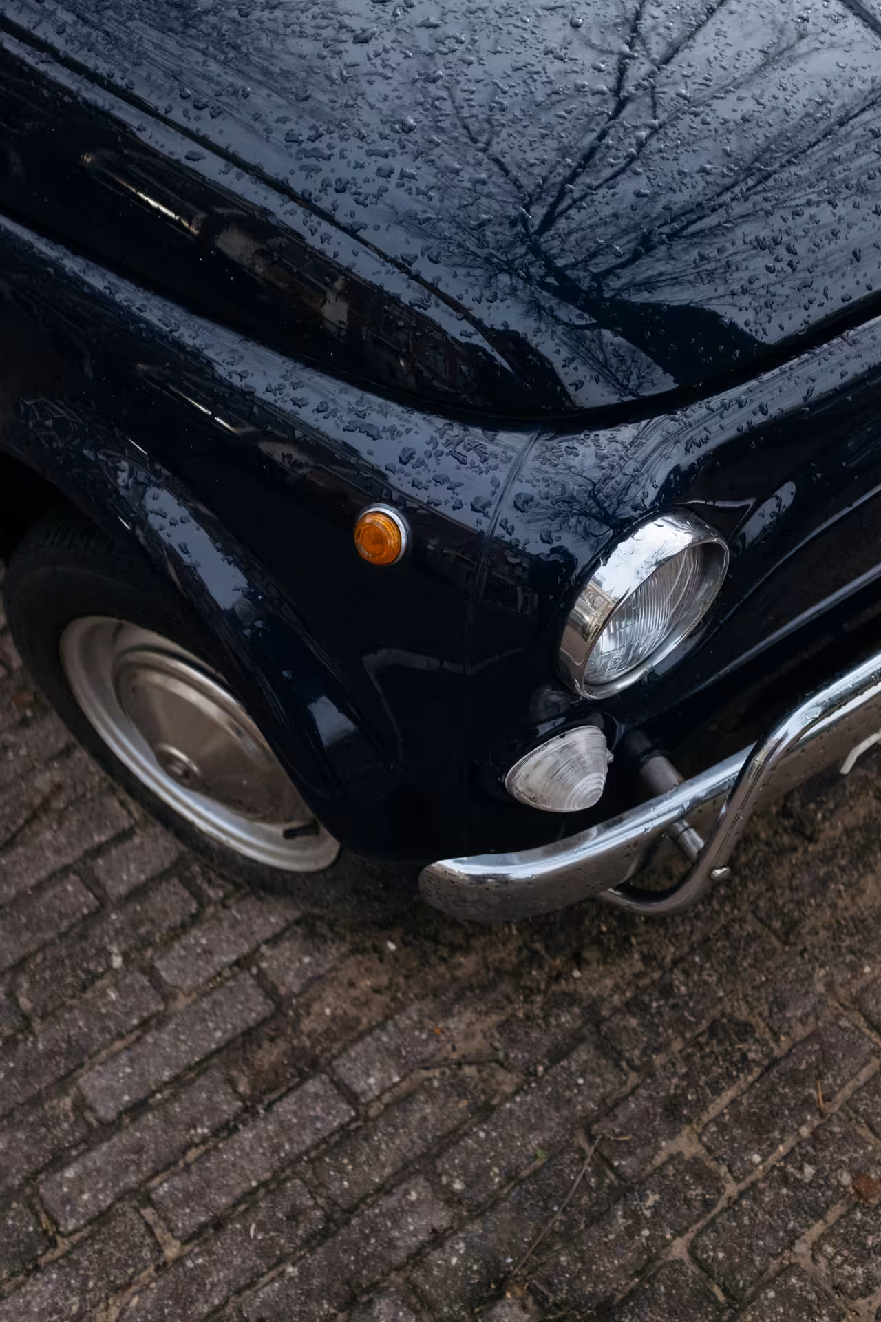 Close-up of a classic Fiat 500 in the rain, highlighting vintage charm for the Roman Hills Vintage Tour.