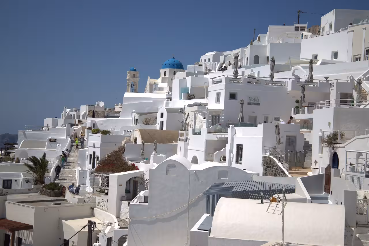 Fira Santorini whitewashed cliffside with blue-domed church, on Shore to Oia tour for cruise guests