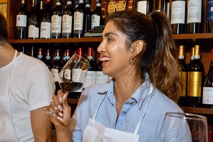 Woman laughing and holding a glass of wine in a cozy Florence cooking class wine cellar.