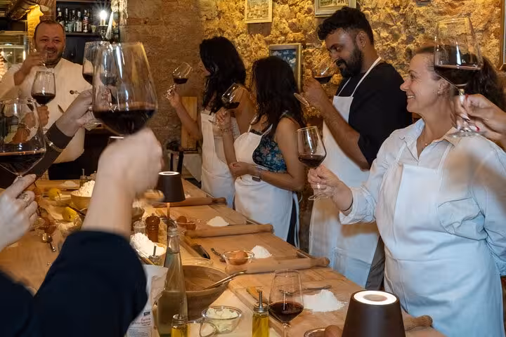 Group toasting with red wine at Florence pasta and tiramisu cooking class, enjoying a lively culinary experience.
