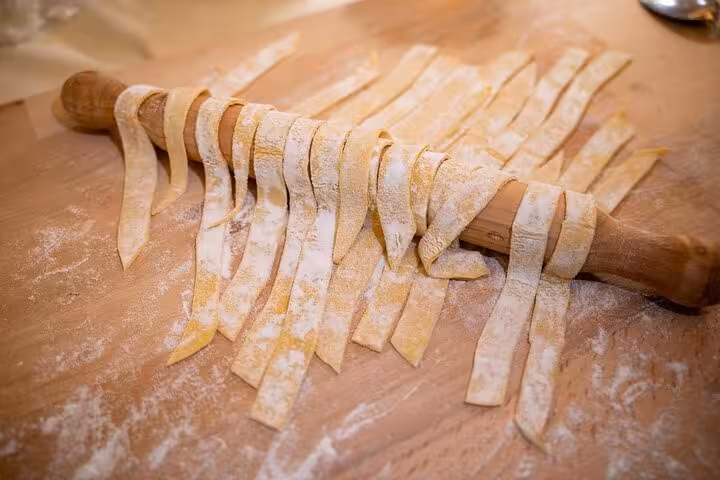 Freshly cut pasta strips draped over a rolling pin, highlighting hands-on learning in a Florence cooking class.