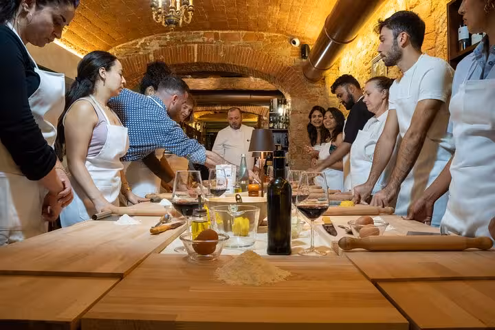 Participants gathered around a table with ingredients at a Florence cooking class for pasta, tiramisu, and wine.