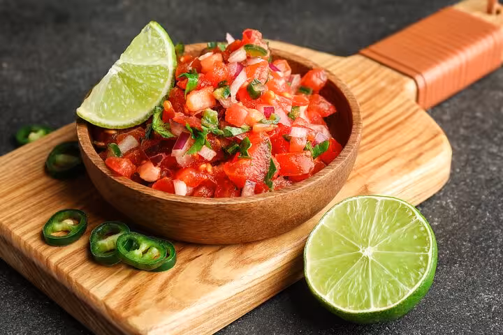 Fresh salsa with lime and jalapeño on a wooden board, highlighting a recipe from the Boozy Panamanian cooking class.