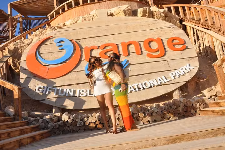 Friends posing at Orange Bay Giftun Island National Park sign on Hurghada boat trip with snorkeling and lunch