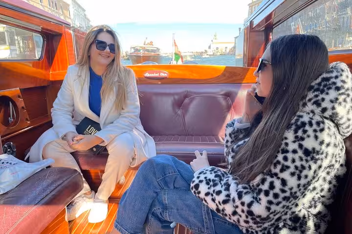 Two friends relaxing on a private water taxi in Venice, enjoying the scenic journey to Chioggia Port.