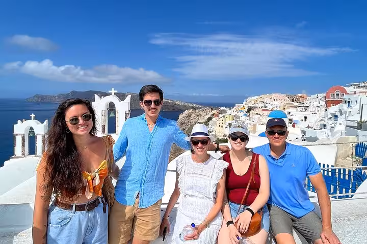 Friends posing in Santorini Oia with caldera view, highlight of 7-day Athens Mykonos Santorini trip