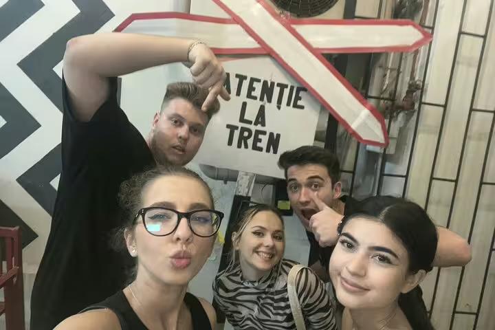Group of five young friends posing for selfie near Atentie La Tren sign in Bucharest