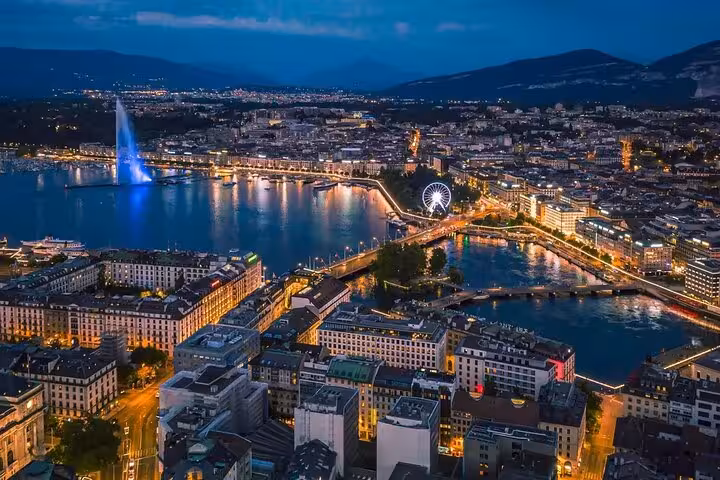 Nighttime aerial view of Geneva with illuminated landmarks and waterfront, ideal for an enchanting Swiss city tour.