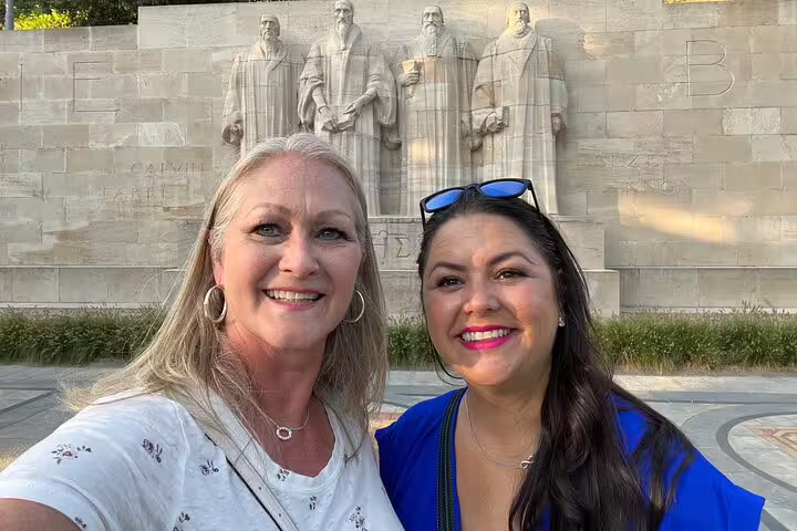 Two travelers smiling at Geneva Reformation Wall, a key stop on the Geneva scavenger hunt walking activity