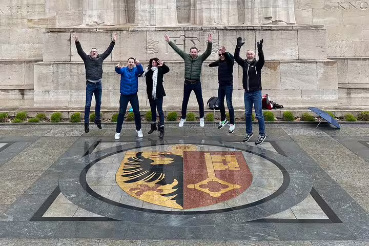 Group jumping on Geneva coat of arms mosaic at Reformation Wall on a scavenger hunt walking tour