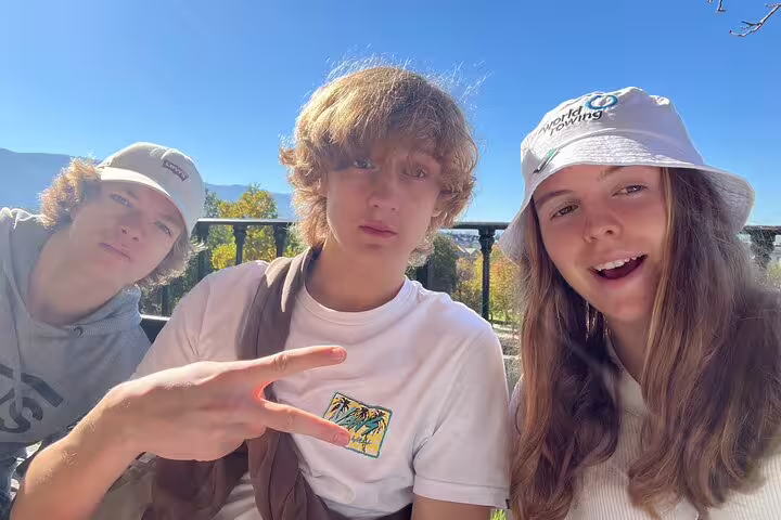 Friends take a selfie on a Geneva scavenger hunt walking tour with lake and Alps views in the background