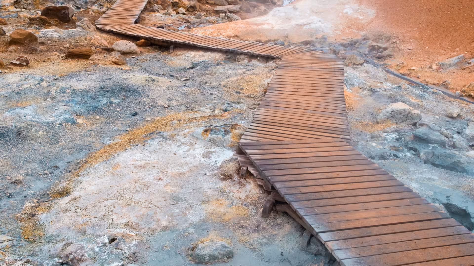 Wooden boardwalk through steaming Krýsuvík geothermal area, Iceland, on guided geothermal sprint hike