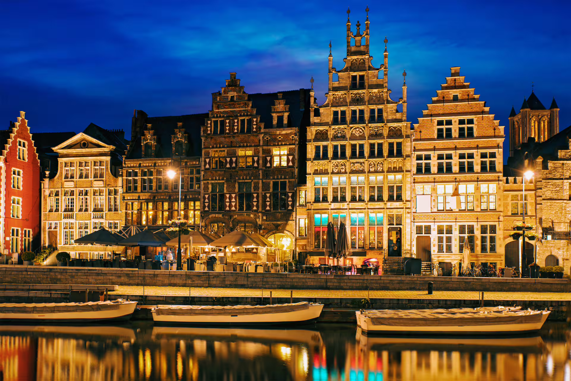 Scenic view of illuminated medieval architecture along Ghent's Graslei waterfront at night during a private walking tour in Flanders.