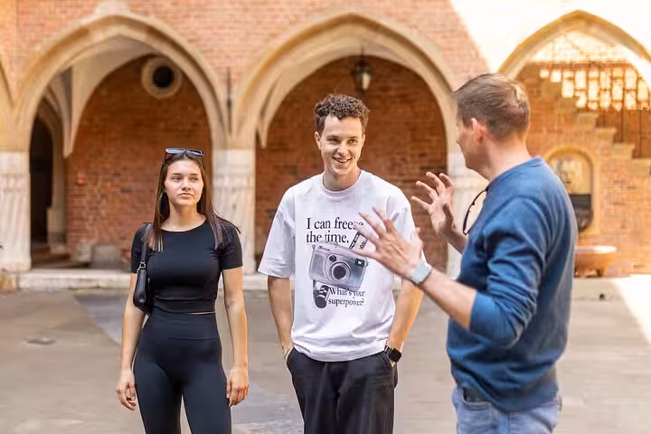 Engaged tourists converse with a guide in a medieval courtyard on the Ghetto and World War II Walking Tour.