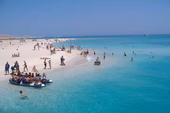 Crowded Giftun Island beach with turquoise Red Sea lagoon, swimmers and boats on full-day snorkeling trip