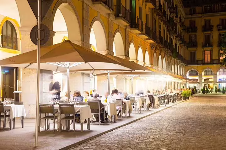 Charming night dining scene under arches at a Girona restaurant, featuring vibrant ambiance and local cuisine experience.