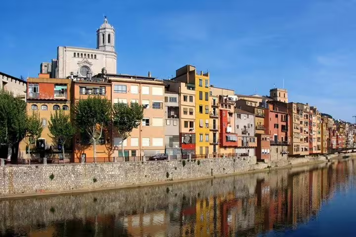 Colorful riverside buildings in Girona with the cathedral in the background, showcasing vibrant local architecture.