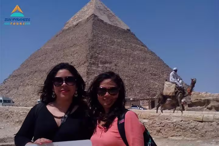 Visitors in front of a Giza pyramid with camel rider, part of Giza, Memphis, Dahshur and Saqqara tour from Cairo