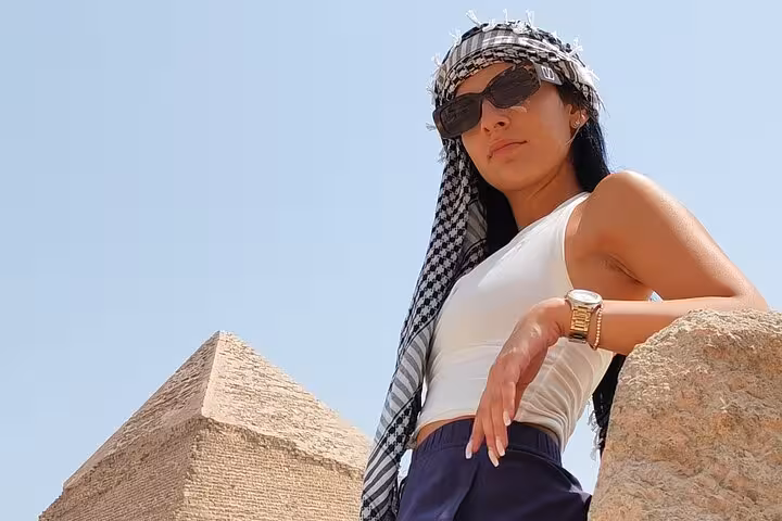 Tourist wearing sunglasses enjoying the view of the Great Pyramid of Giza.