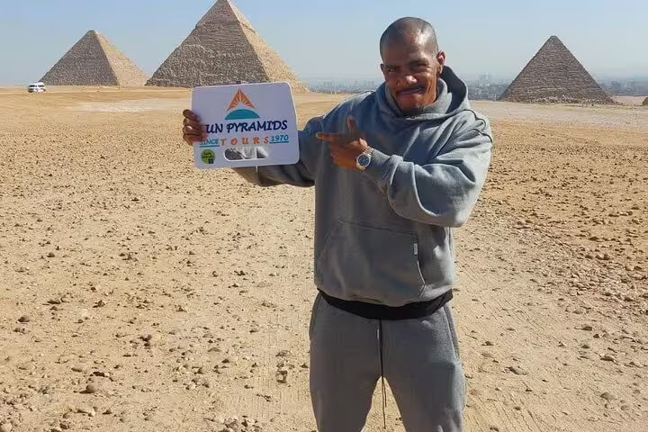 Traveler at Giza Pyramids on private Cairo day trip from Dahab by flight, posing with tour sign