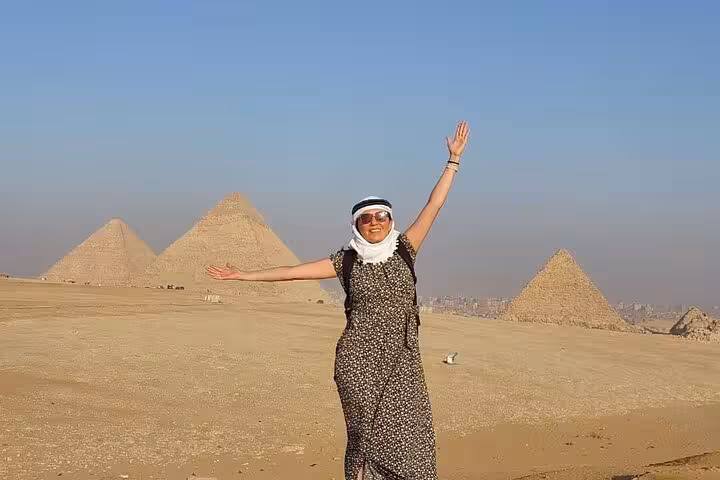 Tour guest posing with arms raised at the Giza Pyramids, classic Cairo desert photo stop on Egypt tour
