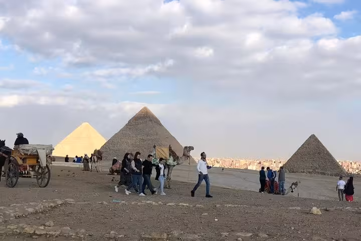Tour group at Giza Pyramids with camel caravan and desert views on private pyramids, ATV, camel ride tour
