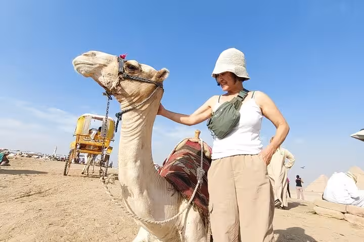 Tourist with camel in Giza desert on private Pyramids trip featuring camel ride, quad biking adventure, lunch and tickets