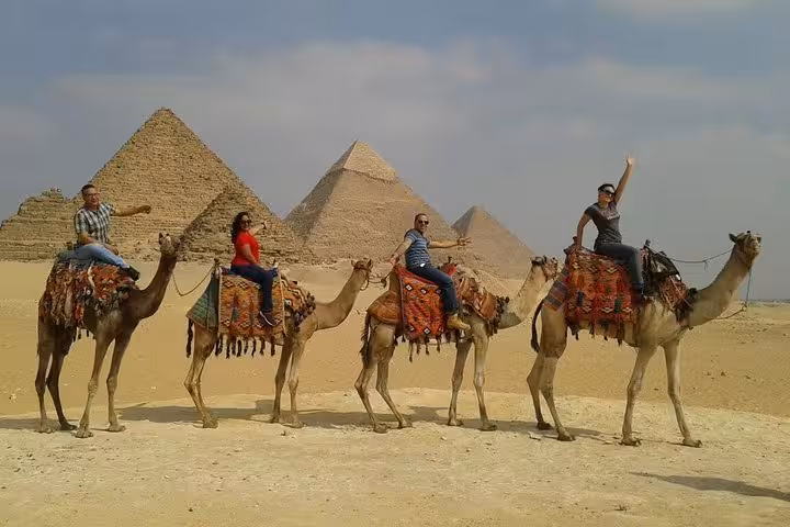 Group camel safari in Giza desert with pyramids backdrop, Cairo day trip to pyramids, citadel and bazaar