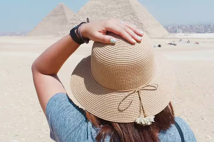 Traveler in sun hat viewing the Giza Pyramids, Egypt, on a day tour with scenic desert panorama in Cairo