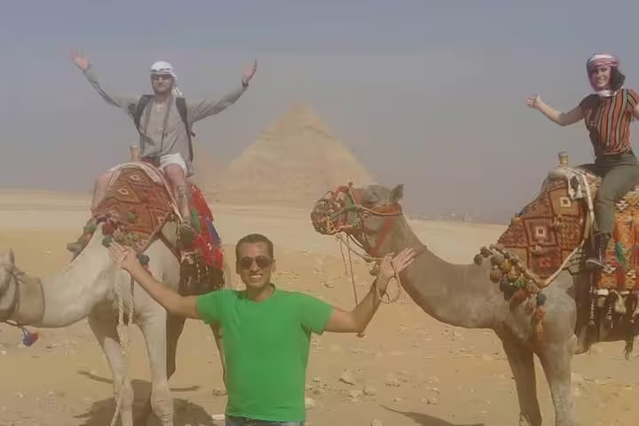 Friends on decorated camels with the Great Pyramid behind, perfect for a Giza sunset or sunrise camel ride tour