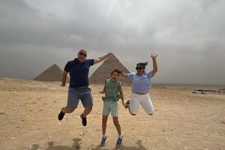 Family jumping in front of Giza Pyramids on private tour with quad bike ride, camel option, lunch and tickets