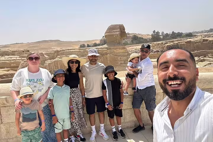 Family group selfie with Egyptologist guide at the Great Sphinx overlook during a Giza Pyramids half-day tour