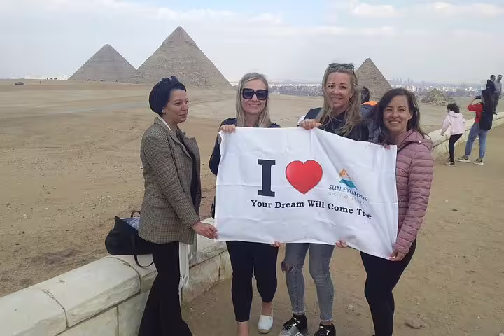 Group photo with banner at Giza Pyramids viewpoint, memorable stop on 2-day Cairo and Giza tour from Alexandria
