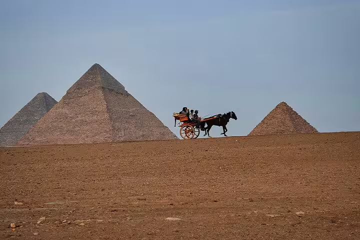 Horse-drawn carriage rides across the Giza Plateau with pyramids in view on a half-day Cairo tour