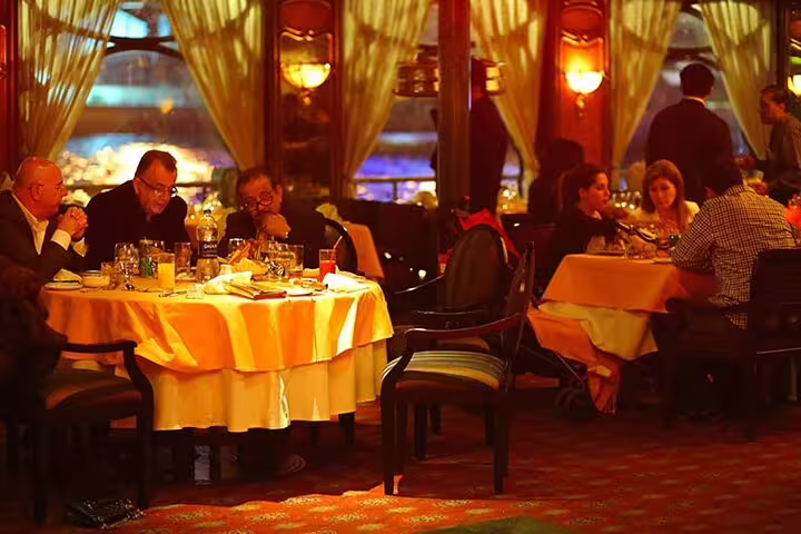 Guests enjoying Nile dinner cruise buffet in Cairo with panoramic windows, included in Giza pyramids and museum tour