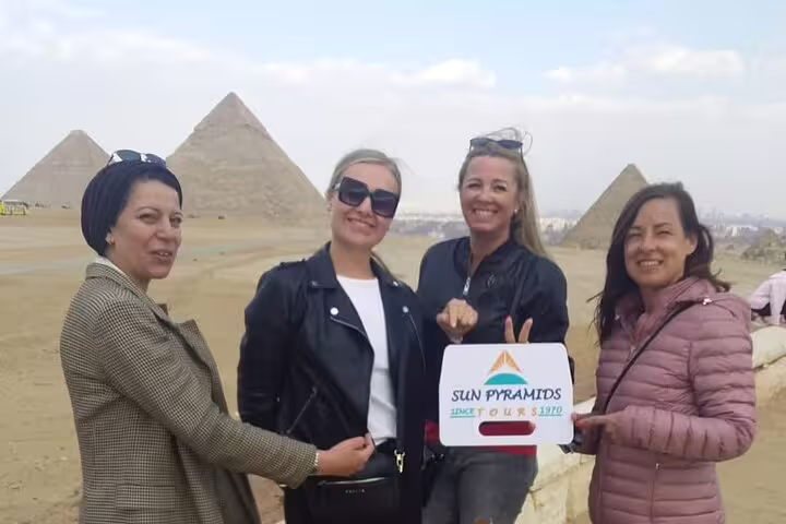 Group of travelers posing at Giza Pyramids on private tour, no hidden costs, Cairo desert panorama in background