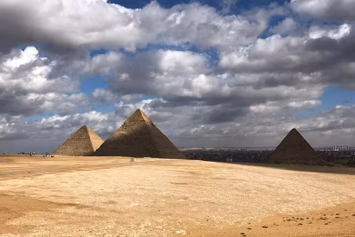 Wide view of the Giza Pyramids under dramatic clouds, private pyramid and Sphinx tour with ATV and camel ride