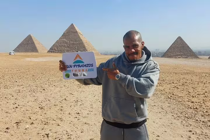 Private guided tour at Giza Pyramids near Cairo airport pickup, traveler posing with pyramids backdrop