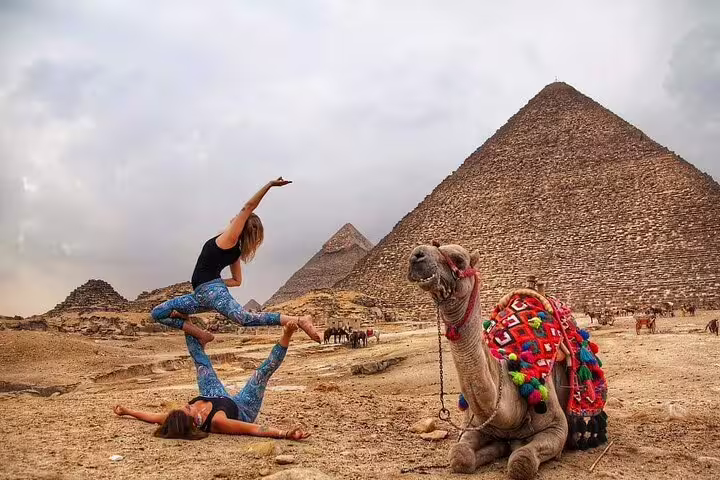 Camel resting by the Giza Pyramids with travelers, ideal for a 3-hour private camel tour including the Sphinx