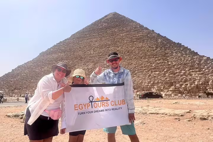 Tourists holding Egypt Tours Club banner at Giza Pyramids, private guided tour to Sphinx and Egyptian Museum