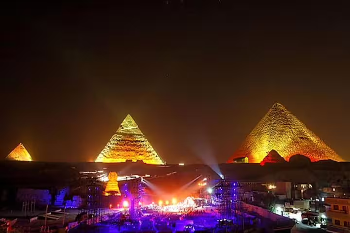 Giza Pyramids and Sphinx glowing at night during Sound and Light Show tour from Cairo with stage lights
