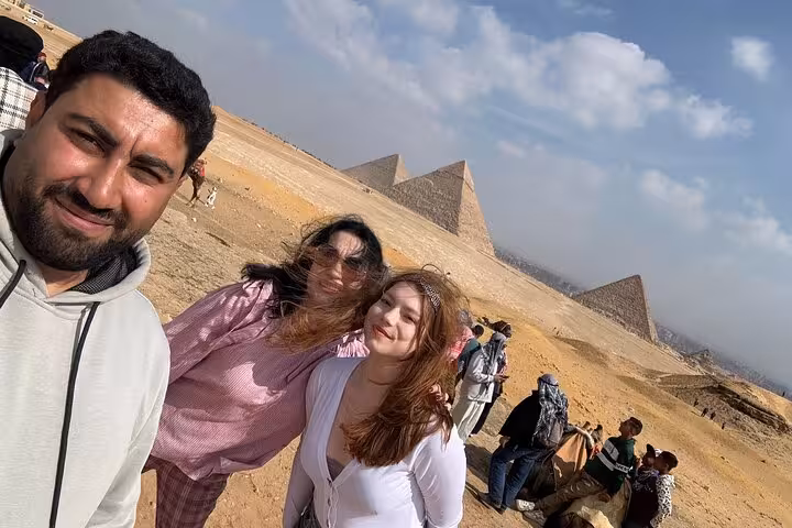 Travelers selfie with local guide at the Giza Pyramids plateau, part of a private Giza Sphinx and Grand Egyptian Museum tour