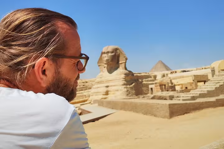 Tourist admiring the Great Sphinx of Giza under the clear sky.