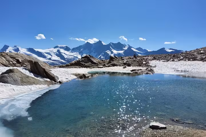 Glacial lake and snowy peaks on Swiss Alps trekking route, 4-day Swiss Magic Through the Alps tour