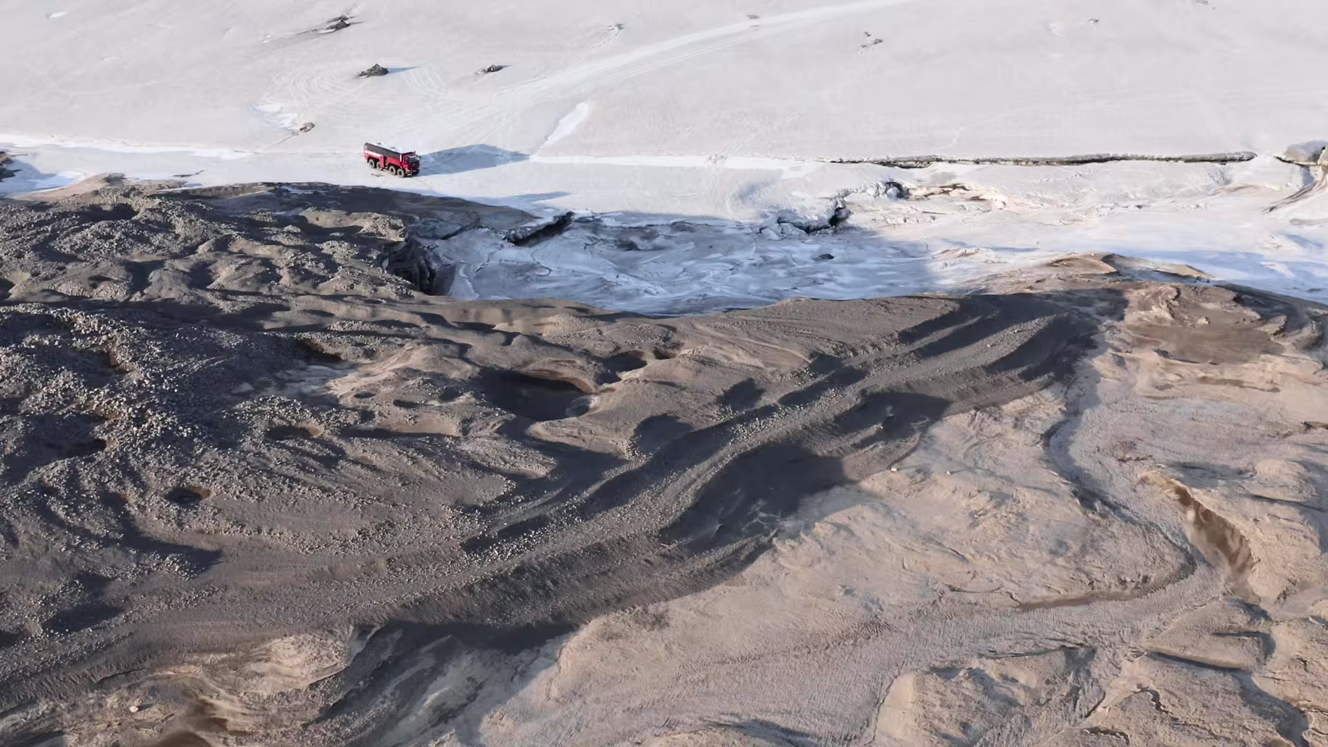 Aerial view of glacier monster truck crossing Langjökull ice and volcanic sand on the Ice Cave tour from Gullfoss