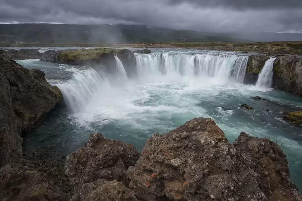 Godafoss waterfall with turquoise waters and dramatic cloudy skies, Diamond Circle Iceland
