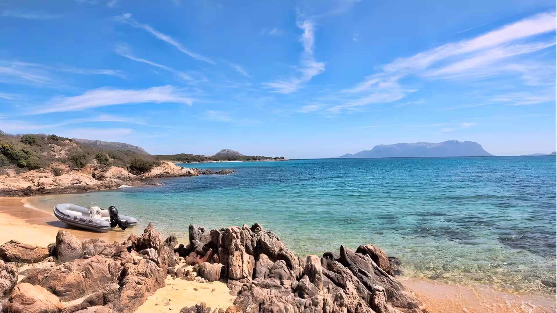Scenic view of Golfo Aranci beach with a RIB boat on the shore, ideal for dolphin watching tours.