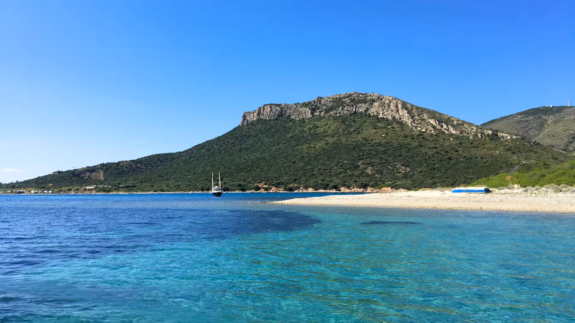 Idyllic coastal view of Golfo Aranci with turquoise waters and lush hills, perfect for a RIB tour adventure.